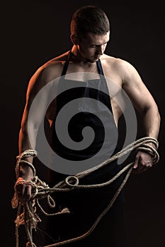 Muscular man in apron with rope