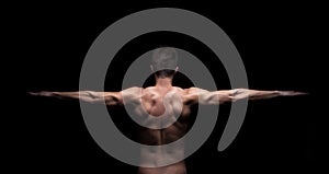 Muscular man with arms stretched out on black background