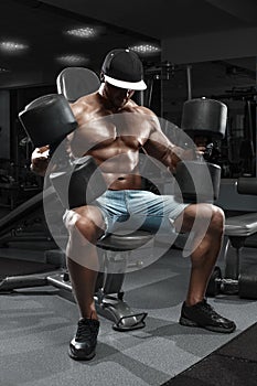 Muscular man with big dumbbells working out in gym, doing exercise