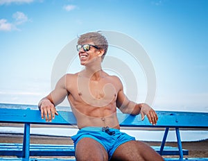 muscular man in a blue shorts and sunglasses.