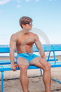 muscular man in a blue shorts and sunglasses.