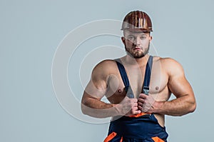 muscular man builder in engineer boilersuit and protective hard hat, building, copy space