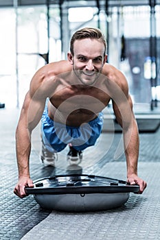 Muscular man doing bosu ball exercises