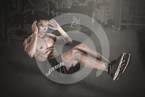 Muscular man doing crunches exercises on the floor