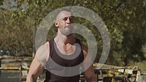 Muscular man doing dumbbell shoulder fly outdoors