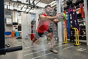 Muscular man doing exercise with medicine ball in crossfit gym.