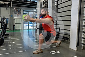 Muscular man doing exercise with medicine ball in crossfit gym.