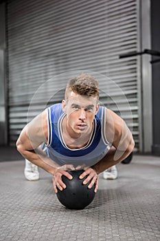 Muscular man doing pull up with medicine ball