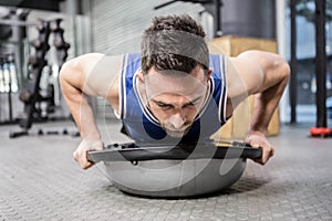 Muscular man doing push up on bosu ball