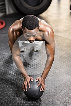 Muscular man doing push up with medicine ball