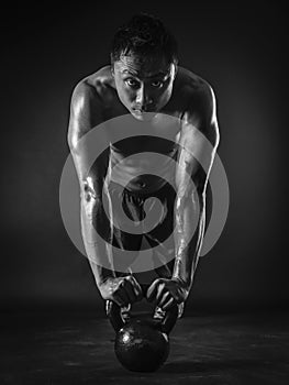 Muscular man doing pushups with kettlebell