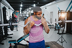 Muscular man doing weight lifting exercise at gym with copy space. Side view of fit african american guy standing with