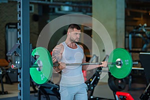 Muscular man doing workout with dumbbells in gym. Handsome man with big muscles posing in the gym. Muscular sportsman