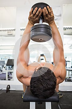 Muscular man exercising with dumbbells in gym