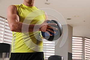 Muscular man exercising with medicine ball in gym, closeup
