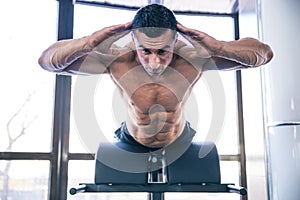 Muscular man flexing back muscles on bench