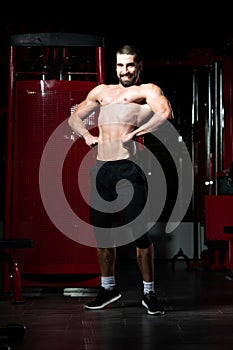 Muscular Man Flexing Muscles In Gym