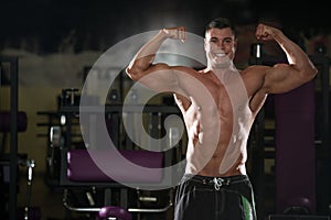 Muscular Man Flexing Muscles In Gym