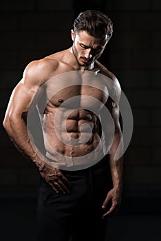 Muscular Man Flexing Muscles In Gym