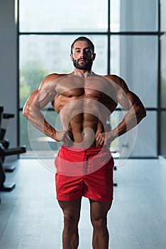 Muscular Man Flexing Muscles In Gym