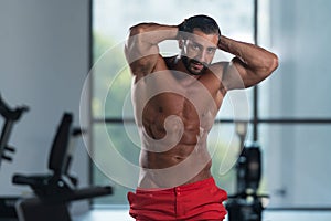 Muscular Man Flexing Muscles In Gym