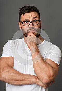 Muscular man in glasses with hand on his chin