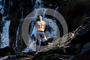 muscular man going to swim in waterfall water. Flow of dollars. Profit business concept. businessman undressing at