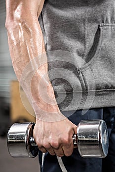 Muscular man with grey jumper holding dumbbell