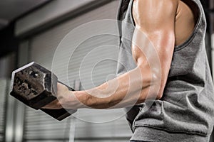 Muscular man with grey jumper lifting dumbbell