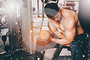 Muscular man in gym doing exercises with dumbbells, strong male