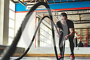 Muscular man in the gym with ropes doing exercises. Crossfit