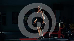 Muscular man in the gym, training legs jumping with a rope with the concept of bar selection of fitness and bodybuilding