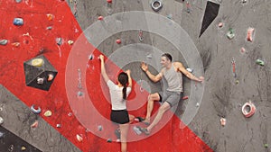 Muscular man helping his girlfriend at climbing wall.