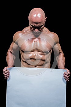 Muscular man holding blank paper