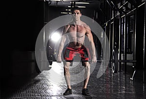 Muscular man lifting a barbell in crossfit gym.