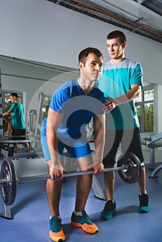 Muscular Man Lifting Deadlift In The Gym with instructor