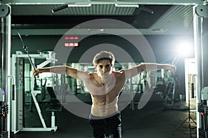 Muscular man lifting weights in fitness gym center