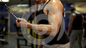 Muscular man looking at his biceps during gym pull-downs, fitness leisure, sport