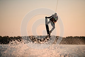 muscular man making trick in jump time with wakeboard against the backdrop of the sky