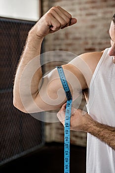 Muscular man measuring biceps