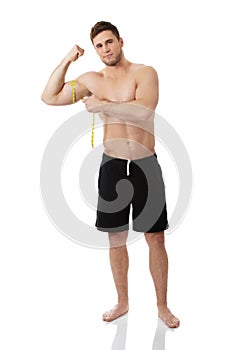 Muscular man measuring his biceps.