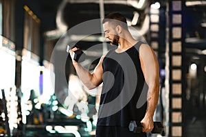 Muscular Man Performing Dumbbell Curls at Modern Gym
