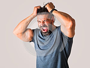 Muscular man posing with angry, frustrated expression screaming,