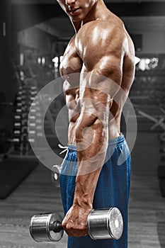 Muscular man posing in gym, showing triceps. Strong male naked torso abs, working out, focus on the hand