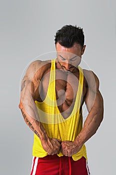 Muscular man pulling down tanktop on torso