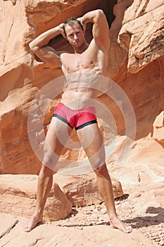 Muscular man on red rocks