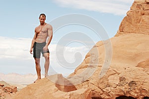 Muscular man on red rocks