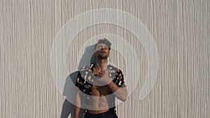 muscular man in a shirt posing against a wall