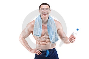 Muscular man smiling with blue towel over neck, drinking water, isolated on white background