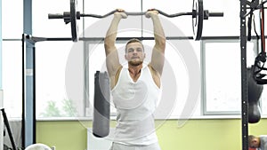 Muscular man on strength training in the gym. Athlete makes triceps exercise with a barbell